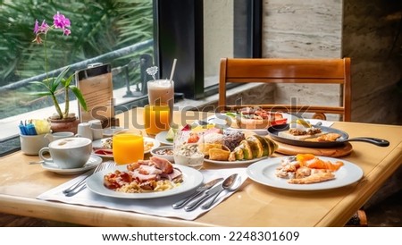 Breakfast in luxury hotel. Table full of various food from buffet in modern resort. Morning food - fresh bakery, glasses of orange juice, eggs, cold cuts and plate with tropical fruits in restaurant