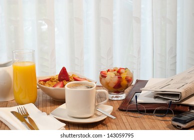 Breakfast Meeting At Table With Cereal, Fruit Salad, Juice And Newspaper And Glasses