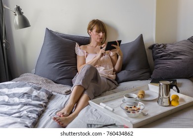 Breakfast and morning news- women reading morning  news on her tablet in bed