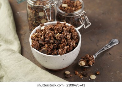 Breakfast muesli cereal with chocolate chips and nuts in several jars and bowl, bottle of milk, brown wooden surface - Powered by Shutterstock