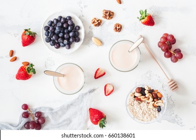Breakfast with muesli, yogurt, strawberry, blueberry, nuts on white background. Healthy food concept. Flat lay, top view