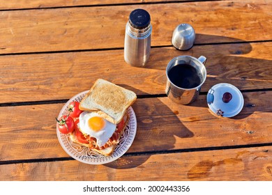 Breakfast in nature. Fried sandwich with egg, bacon, tomatoes and hot coffee from a thermos - Powered by Shutterstock