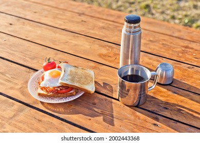 Breakfast in nature. Fried sandwich with egg, bacon, tomatoes and hot coffee from a thermos - Powered by Shutterstock