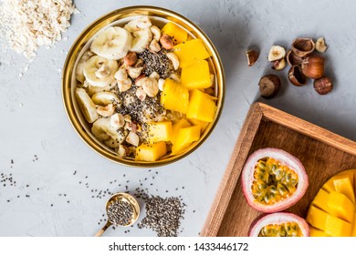 Breakfast Oatmeal Porridge With Fresh Fruits, Chia Seeds And Hazelnut On Gray Background. Oatmeal With Mango And Banana. Healthy Breakfast Concept. Flat Lay, Top View. Mockup, Overhead, Copy Space