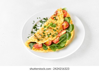 Breakfast omelette with spinach and tomato on white plate, close up view