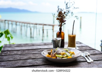 Breakfast on a wood table with a beach front view. French toast for breakfast with sea view. Perfect place for a breakfast. Delicious.