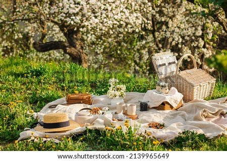 Breakfast picnic with waffles and tea in spring blossom garden on a white tablecloth on a sunny day, cherry blossoms. Outdoor, picnic, brunch, spring mood