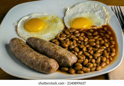 breakfast plate  of fried eggs sausage and baked beans - Shutterstock ID 2140899637