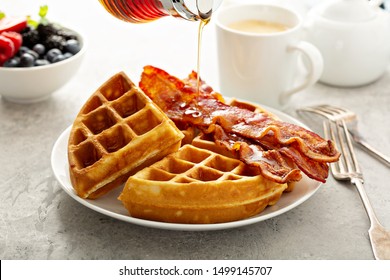 Breakfast plate with waffles and bacon, berries and maple syrup