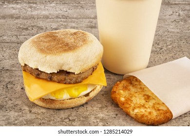 Breakfast Sandwich With Coffee And Hash Brown On Concrete Table. English Muffin, Egg, Cheese And Sausage.