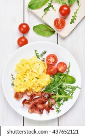 Breakfast With Scrambled Eggs, Bacon And Vegetable Salad On White Wooden Background, Top View