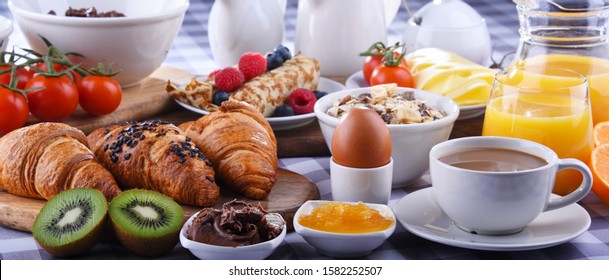 Breakfast served with coffee, orange juice, croissants, pancake, egg, cereals and fruits.