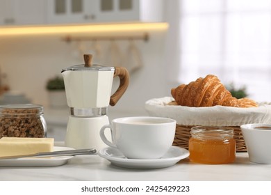 Breakfast served in kitchen. Fresh coffee, granola, croissants, jam, butter and honey on white table