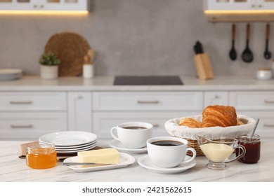 Breakfast served in kitchen. Fresh croissants, coffee, butter, jam, honey and sweetened condensed milk on white table - Powered by Shutterstock