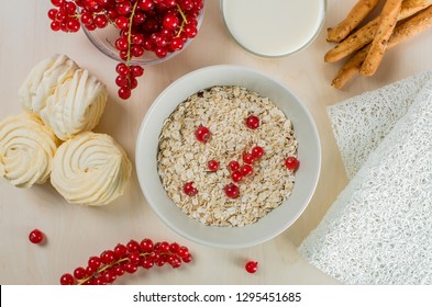 Breakfast Served With Oatmeal, A Glass Of Milk, Bread Sticks, Cranberry And Marshmallow On A Wooden Background. Flatlay