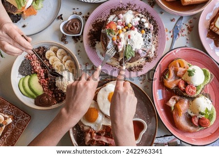 Breakfast is served with various dishes including eggs, bacon, pancakes and fruits on a colorful table.
