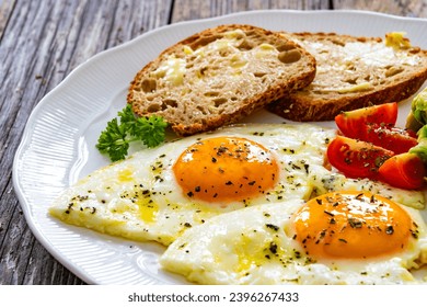 Breakfast - sunny side up egg, toasted bread and avocado served on wooden table  - Shutterstock ID 2396267433