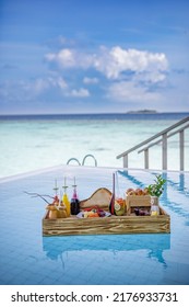 Breakfast In Swimming Pool, Floating Breakfast In Luxurious Tropical Resort. Table Relaxing On Calm Pool Water, Healthy Breakfast And Fruit Plate By Resort Pool. Tropical Couple Beach Luxury Lifestyle