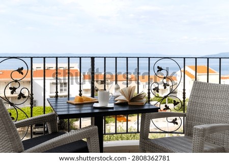 Breakfast table on a balcony overlooking red rooftops and the Adriatic Sea in Makarska, Croatia. Peaceful travel lifestyle scene