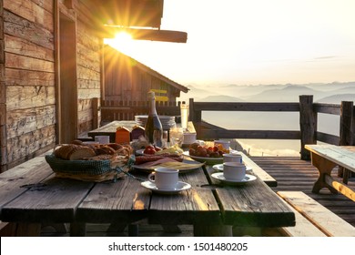 Breakfast table in rustic wooden terace patio of a hut hutte in Tirol alm at sunrise