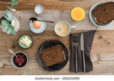 Breakfast table shot from above with bread, egg, coffee, orange juice and jam