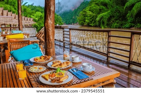breakfast table at a tropical beach house on the River Kwai in Thailand.Wooden floating raft house in river Kwai Kanchanaburi, Thailand, breakfast with eggs bread and coffee