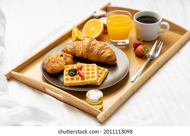 Breakfast in a tray filled with black Coffee, Cheese and chocolate croissant with orange juice with few strawberries
