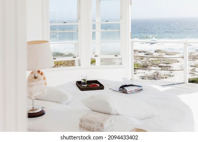 Breakfast tray and magazine on bed overlooking ocean