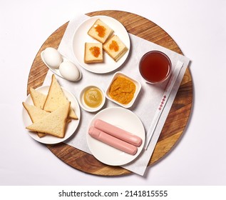 breakfast. two eggs, two boiled sausages, bread with caviar, compote. on a white background