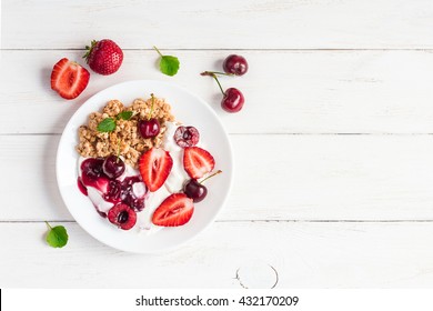 Breakfast with yogurt, muesli and berries on white wooden background. Fresh yogurt. Healthy food concept. Top view, flat lay, copy space - Powered by Shutterstock