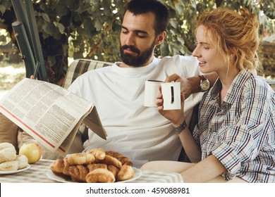 breakfast of young beautiful couple on nature. man and woman reading a newspaper together. - Powered by Shutterstock