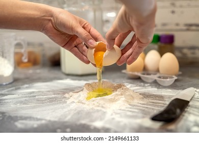 breaking eggs with women's hands into flour to make dough for cakes. The concept of cooking on the desktop