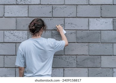 breaking the law: man with a spray paint can painting a wall outdoor, damaging the building  - Powered by Shutterstock