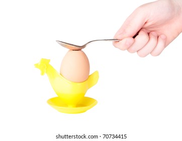 Breaking shell of boiled egg with the spoon