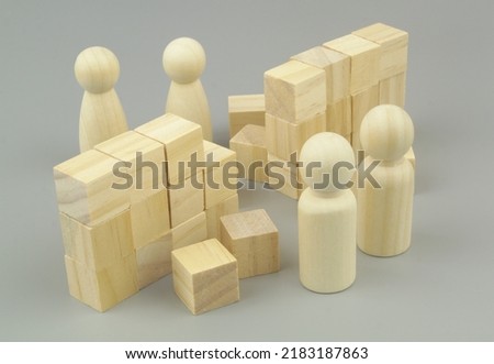 Breaking wall between woman and man people concept. Broken wall made of wooden cubes and wooden female and male people figures.