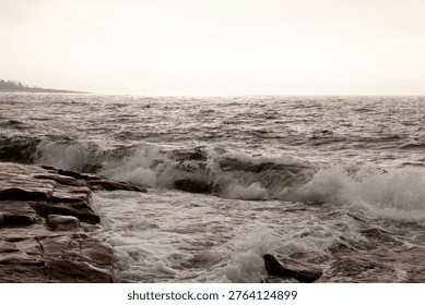 Breaking waves during a windy day. The sea hit the rocky shore and the sea fog; smog rolls in from the colder waters. September, a normal situation.