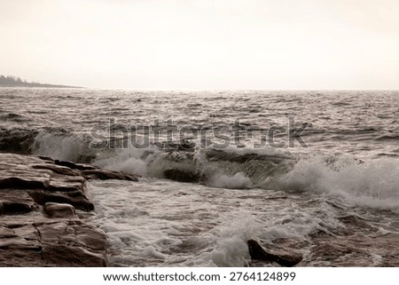 Breaking waves during a windy day. The sea hit the rocky shore and the sea fog; smog rolls in from the colder waters. September, a normal situation.