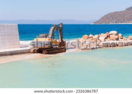 Breakwater construction at coastal  -  Excavator laying stones and Rubble during breakwater construction - Datca
