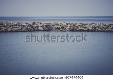 The breakwater in the form of a strip of stones stretches out into the sea.