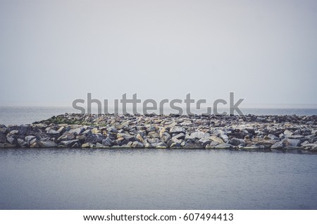 The breakwater in the form of a strip of stones stretches out into the sea.