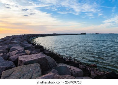 Breakwater with gates and fishing boat leaving harbor at dramatic cloudy sunset - Powered by Shutterstock