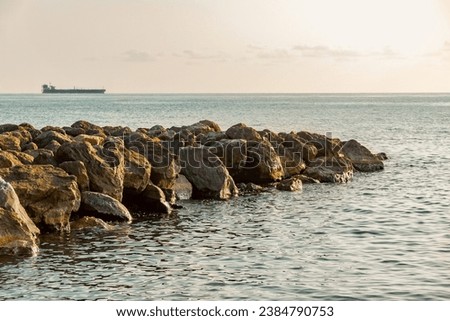 A breakwater made of stones. Seascape. A beach with a breakwater made of large stone boulders. View of the sea breakwater made of stones. A dam near the seashore in summer. Stock fotó © 