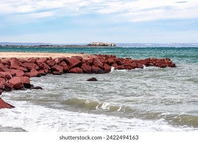 Breakwater on beach in coastal maritime landscape, Sea of Cortez and part of peninsula in background, calm waters on cloudy day in La Paz, Baja California Sur Mexico - Powered by Shutterstock