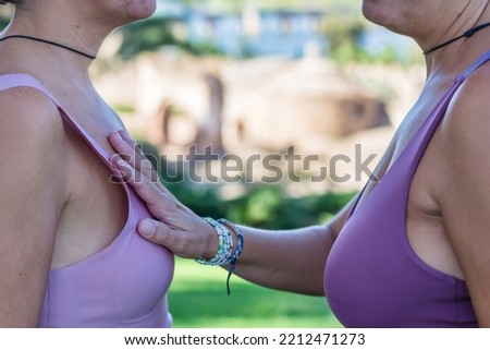 Breast Cancer Awareness Day concept. Two anonymous women facing each other touching breasts. Concept of overcoming. Pink October