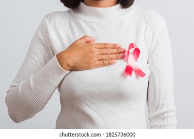 Breast cancer awareness healthcare and medicine concept. Close up Asian woman wear white shirt she have pink breast cancer awareness ribbon and uses handles on chest, isolated on white background