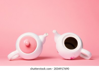 Breast Cancer Awareness Month. Two white porcelain teapots lying on a pink background. One teapot without a lid, symbolizing the disease. Copy space.