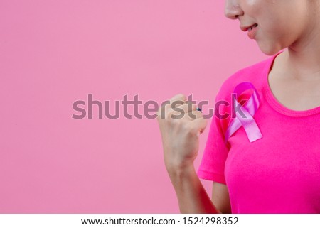 Breast cancer awareness month, Woman in pink t-shirt with satin pink ribbon on her chest, supporting symbol of breast cancer awareness campaign in October.