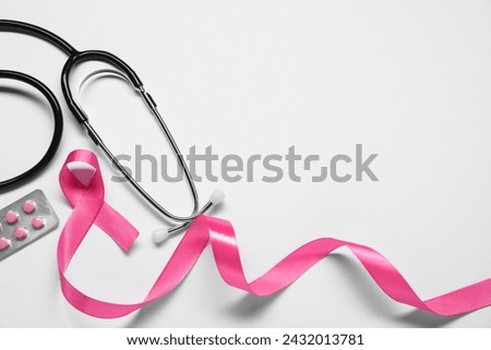 Breast cancer awareness. Pink ribbon, stethoscope and pills on white background, flat lay. Space for text