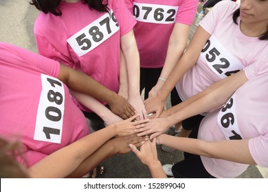 breast cancer awareness race: women in pink  joining hands for support 