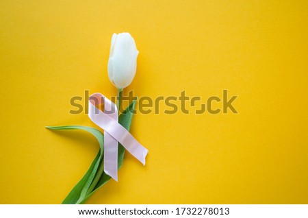 Breast cancer banner with white tulip and pink ribbon on the yellow background. Women health care and prevence of breast cancer, banner with space for text